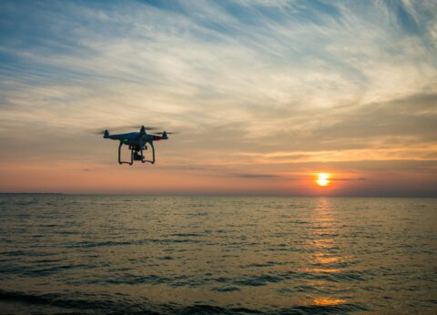 Dron volando sobre el mar al atardecer